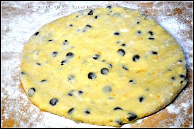 Scone dough, with chocolate chips, is rolled out into circle shape