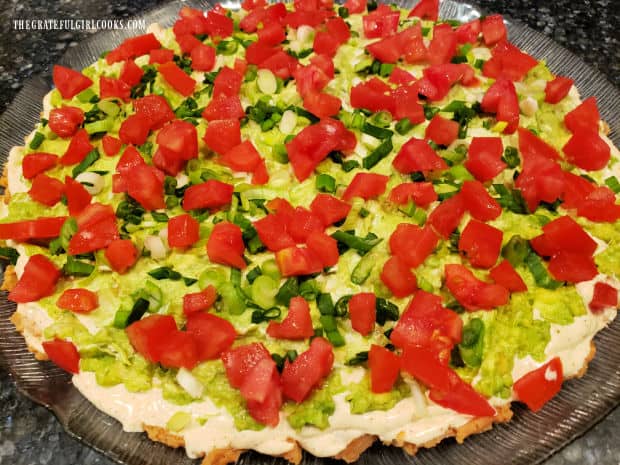 Chopped tomatoes are layered on top of the green onion layer.