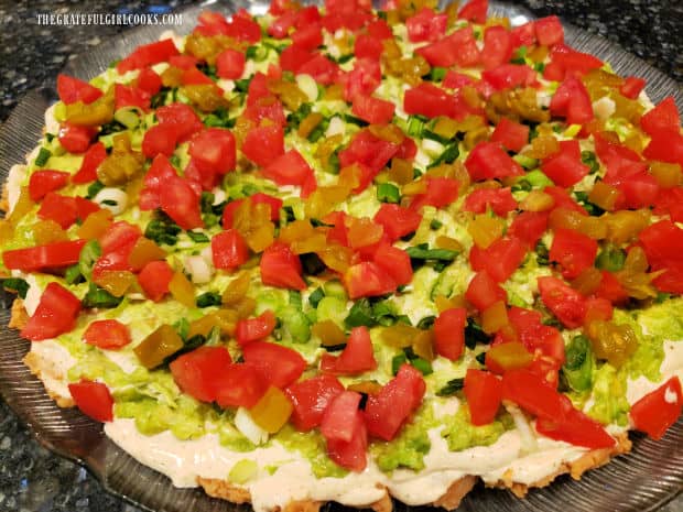 Chopped green chilis are evenly sprinkled on top of the tomato layer.