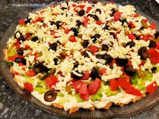 Sliced black olives then grated jack cheese is sprinkled on top of the green chili layer..