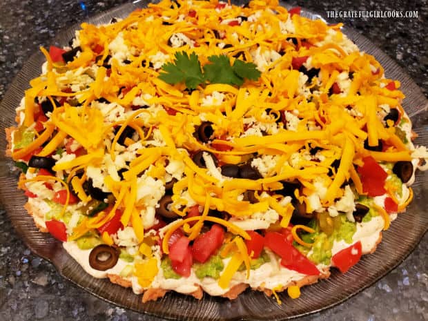 The final layer is grated cheddar cheese on top of the Mexican Layer Dip and a cilantro garnish.