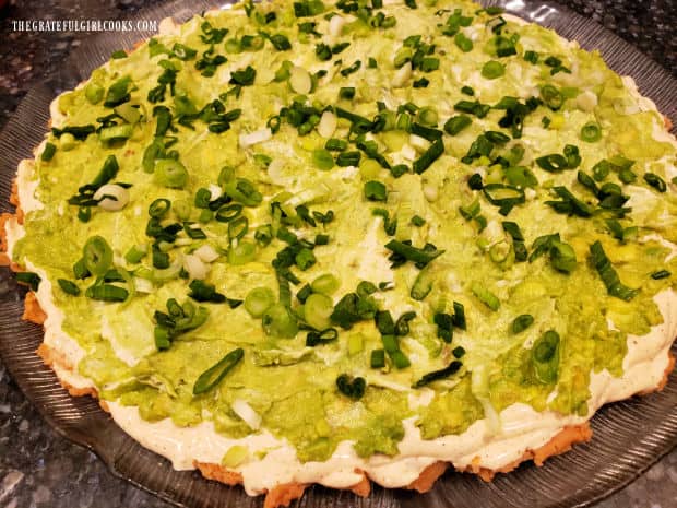 Sliced green onions are sprinkled evenly on top of the avocado layer.