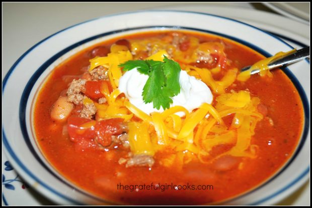 A bowl of Mom's old-fashioned chili, garnished with cheese, sour cream and cilantro.
