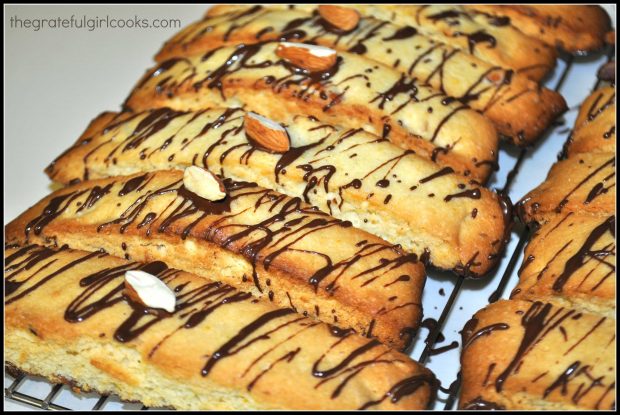 Orange almond biscotti are drizzled with melted chocolate on top.