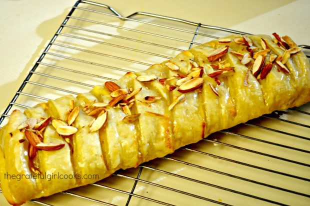 The orange cheese danish pastry is topped with glaze and sliced almonds when done.