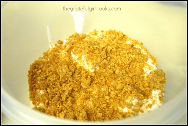 Graham cracker crumbs are added to finished ice cream in a layer.