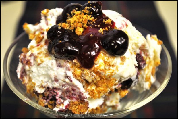 The blueberry cheesecake ice cream is topped with blueberry sauce and graham cracker crumbles to serve.