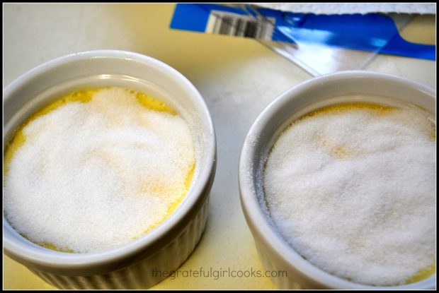 Granulated sugar is spread on the top of each creme bruleé before torching.