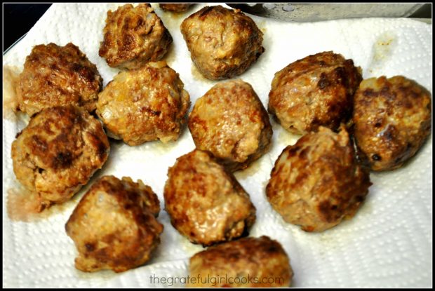 Browned meatballs are drained on paper towels.