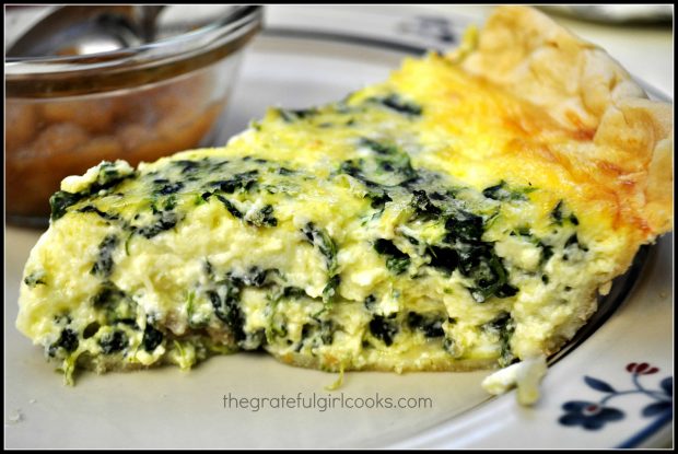 A side view of a slice of Italian sausage spinach quiche on a plate.