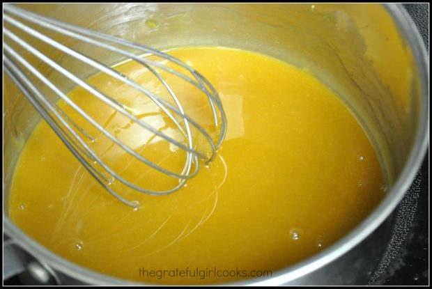 Orange glaze for pork roast is cooked on stove.