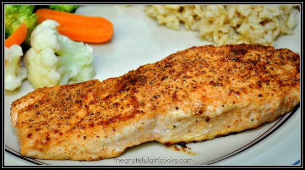 A pan seared creole salmon fillet is served with rice and vegetables on the side.