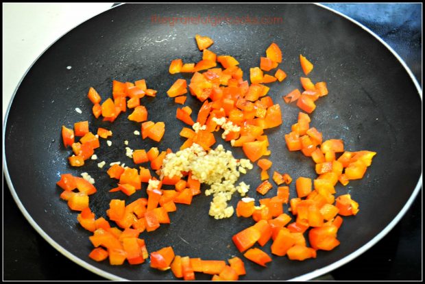 Red bell peppers and garlic cook in skillet before adding more sauce ingredients.