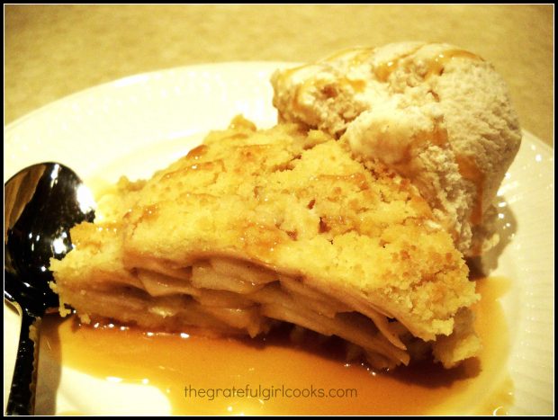 A slice of the apple shortbread tart on plate with spoon and ice cream.