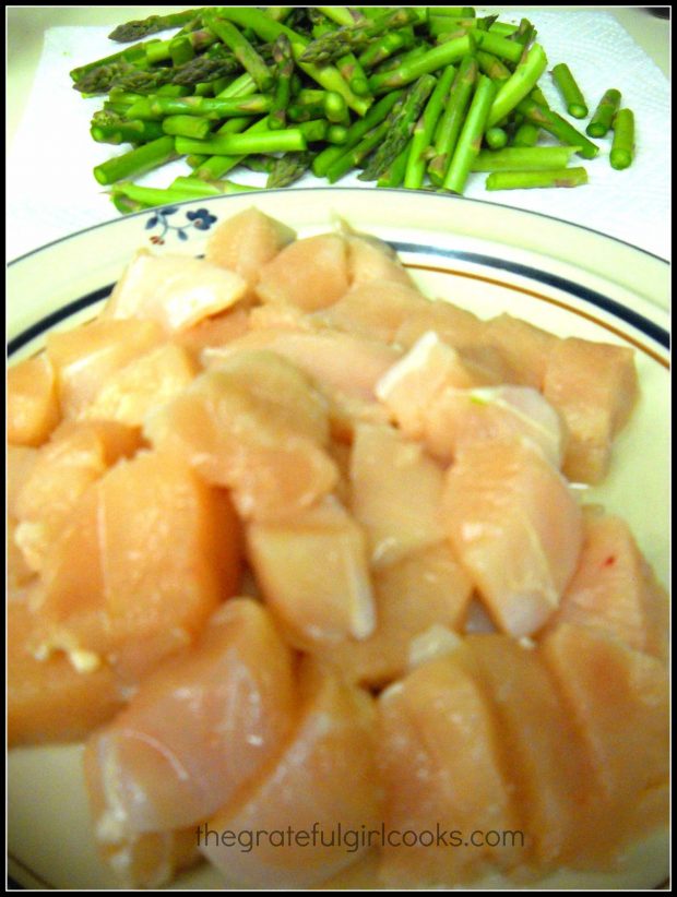 The chicken breast and fresh asparagus are cut into chunks before cooking.