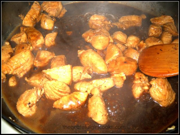 Asian-inspired lemon sauce is added to the cooked, cubed chicken in skillet.