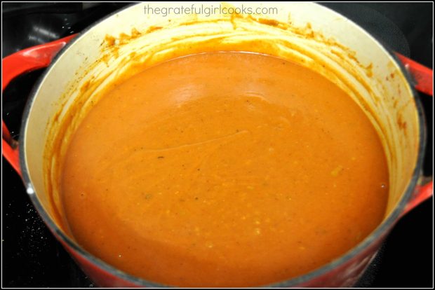 Homemade red sauce for shredded pork smothered burritos is complete after adding tomato paste and sauce to pan.