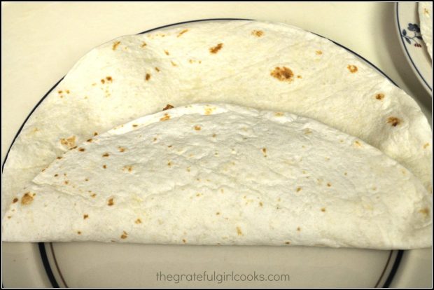 Flour tortilla is folded over the shredded pork filling.