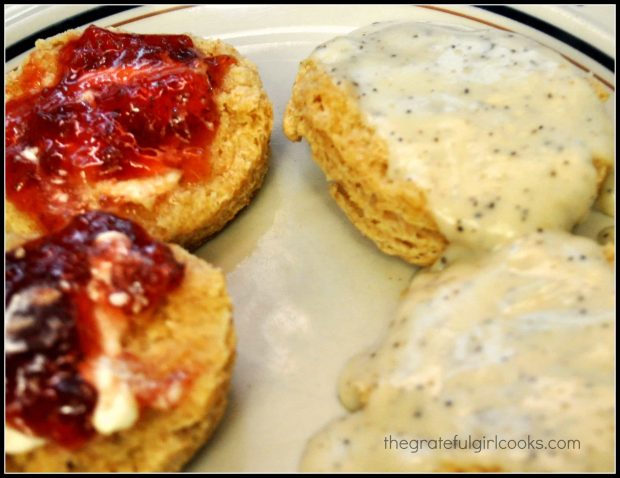 Biscuits topped with gravy, and other biscuits (on the left) topped with jam.