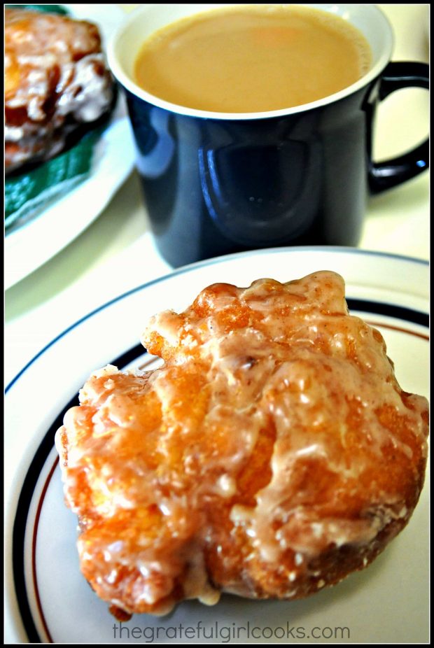 Cup of coffee with one apple fritter on a plate