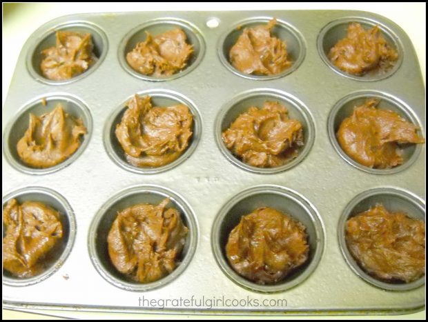 Brownie batter is divided into miniature muffin cups that have been lightly greased.