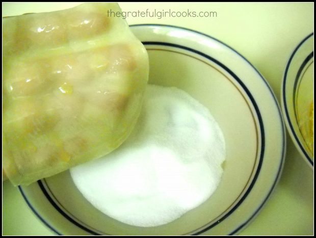 Holding buttered won ton wrapper over bowl of sugar