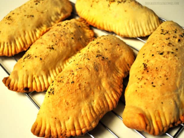 Five, crimped edge fully stuffed calzones, after baking.