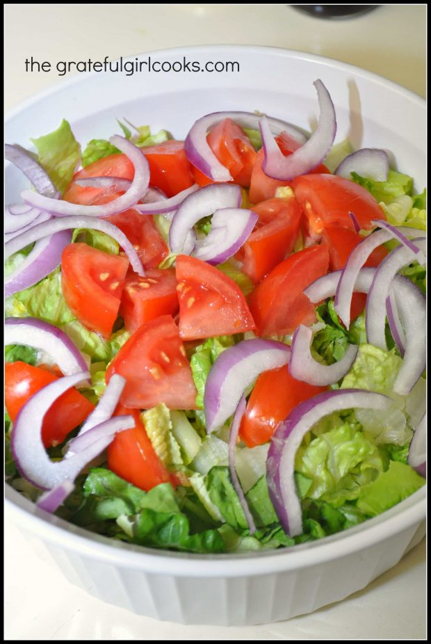 Romaine lettuce, red onion slices and tomatoes go into the Greek salad.