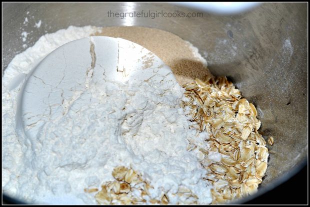 Oats, flour and other bread ingredients in metal mixing bowl