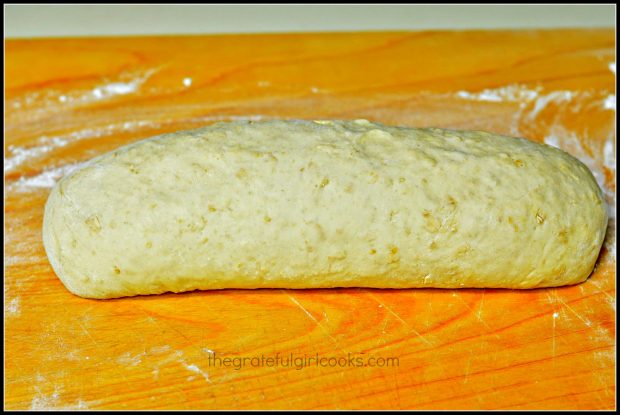 Dough for honey oat bread is rolled into a loaf shape on cutting board