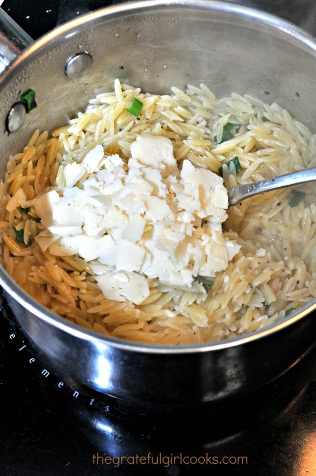 Parmesan cheese is added to cooked orzo pasta.