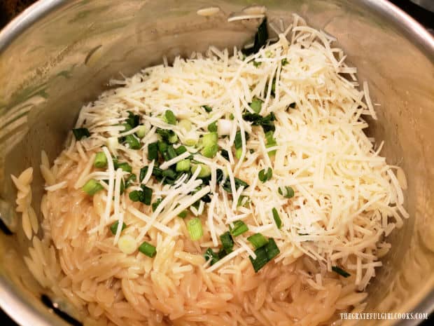 Grated Parmesan cheese and green onions are added to the cooked orzo pasta.