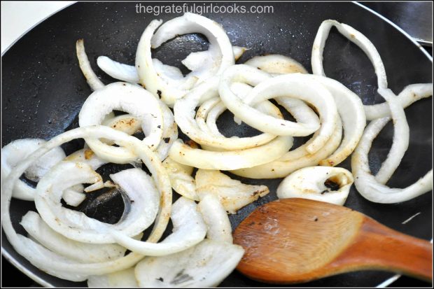 Sliced onions for salisbury steak gravy are cooked in skillet.