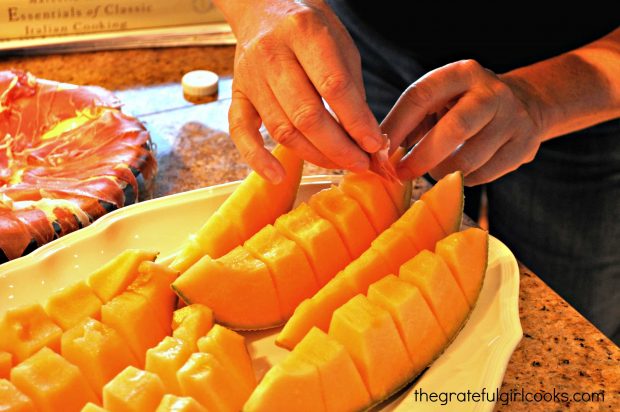 Thin proscuitto slices are placed into sliced cantaloupe wedges