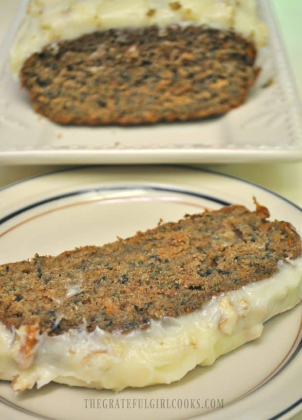 A slice of carrot zucchini bread on a plate, with loaf in background.