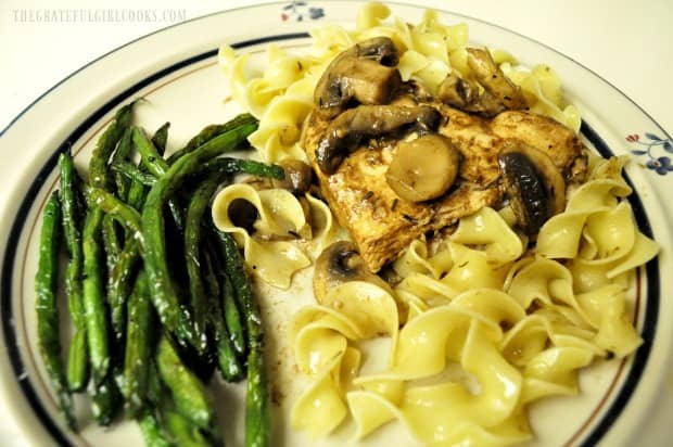 Chicken Marsala is served on a bed of egg noodles, with green beans on the side.