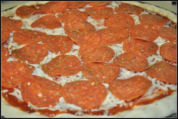 Mozzarella cheese and pepperoni slices are added to pizza.
