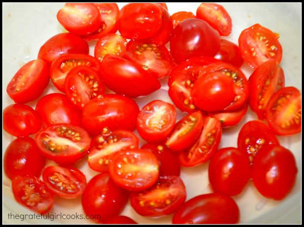 Cherry tomatoes are sliced in half before marinating.