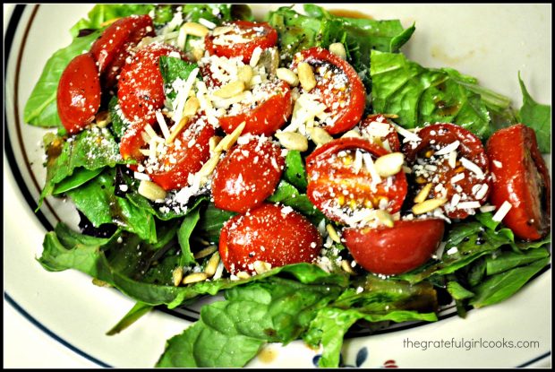 Marinated tomato salad is served on chilled greens, topped with pine nuts and Parmesan cheese!