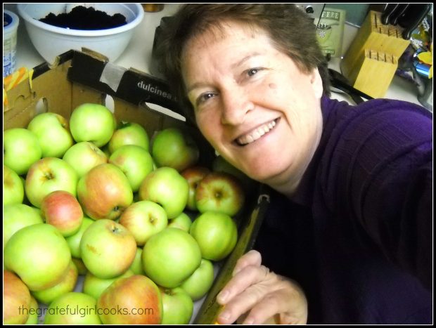 Woman smiling with a box of apples.