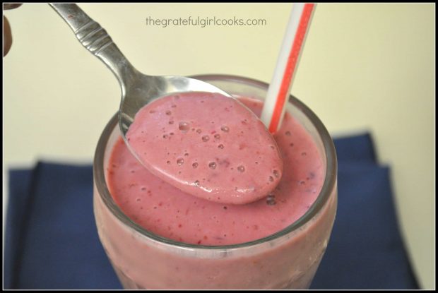 Spoonful of fresh peachberry smoothie in glass with straw