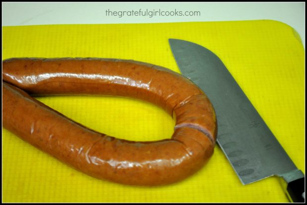 A ring of kielbasa is cut into 1" slices before cooking.