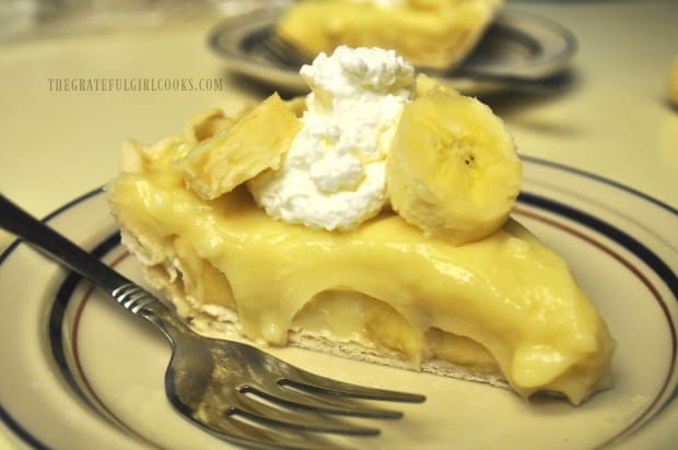 Banana cream pie is served with dollop of whipped cream and banana slices.