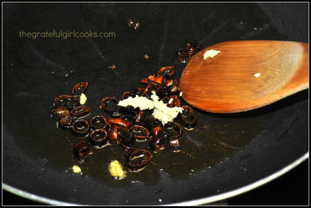 Fresh minced ginger is added to skillet with chili peppers.