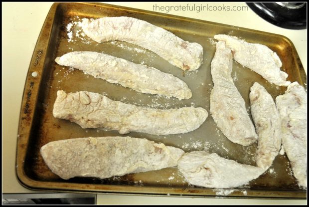 Raw, floured chicken strips on cookie sheet