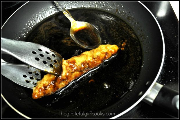 Piece of chicken being covered with Asian lemon sauce in skillet