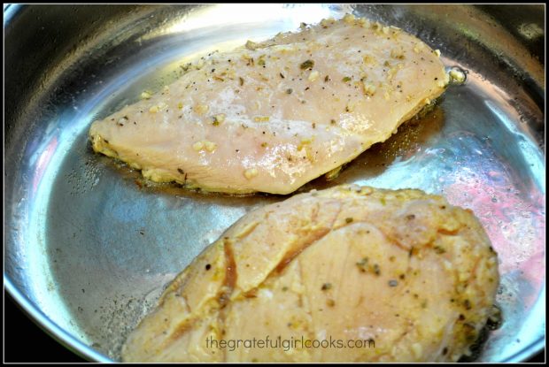 The marinated chicken breasts are pan-seared in a hot skillet.