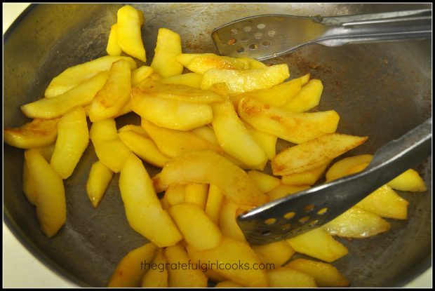 Apples are cooked in a large skillet until golden brown on the outside.