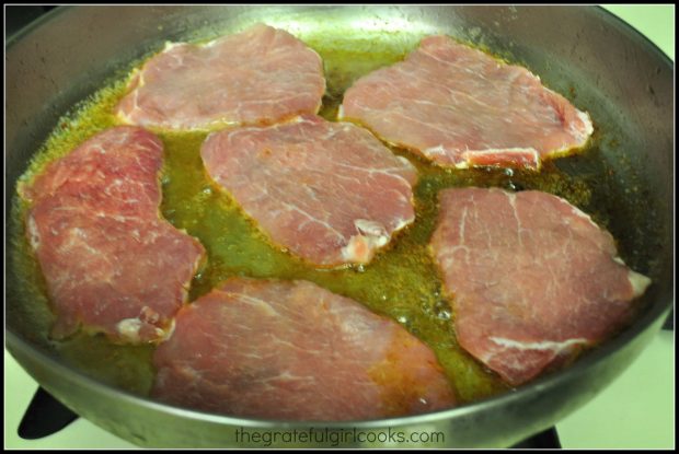 The pork cutlets are cooked in melted butter in a hot skillet.