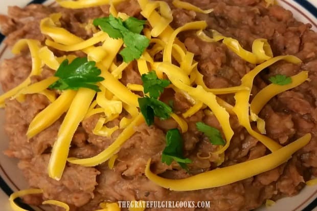 Crock pot refried beans are garnished with cheese and are ready to ea!